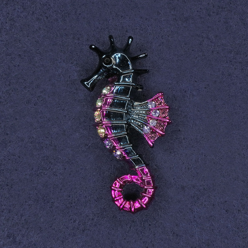 Broșă în formă de cal marin, cu cristale albe și gri, email roz deschis și albastru închis, metal argintiu 26×47 mm