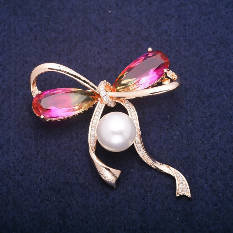 Broșă fundă cu o mărgea perlată și cristale galben-roz în stil Swarovski, metal auriu 45x47 mm